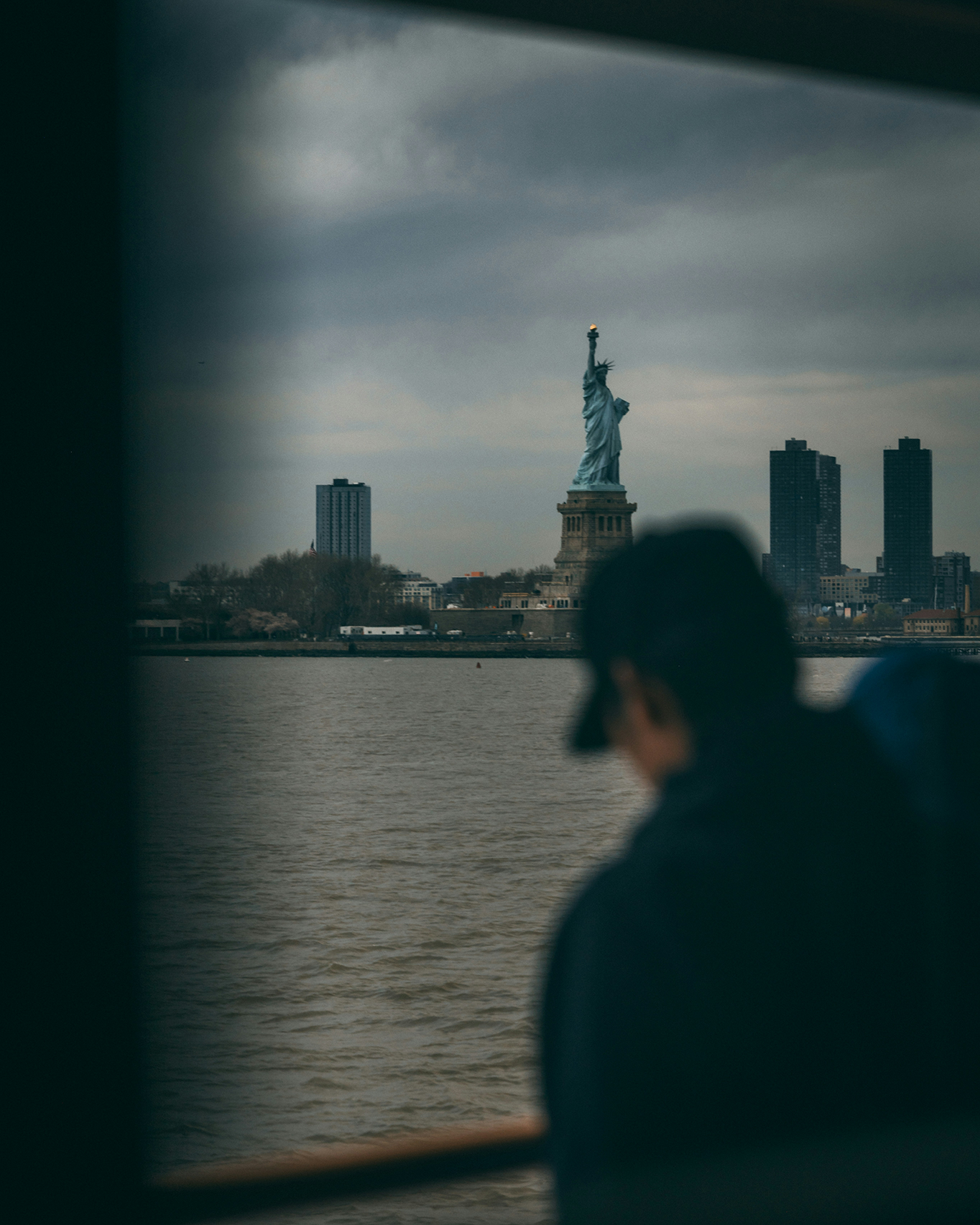 Person viewing Statue of Liberty across harbor representing immigration and freedom