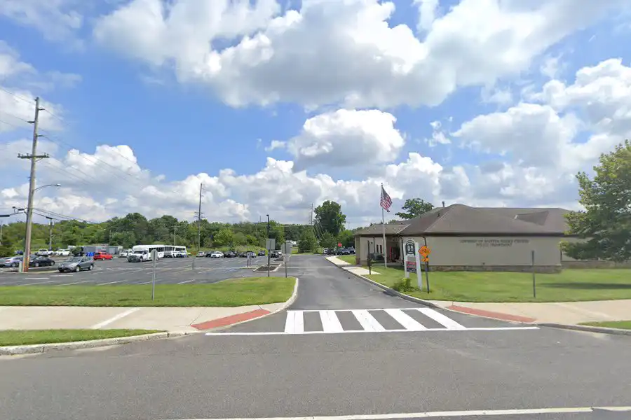 Mantua Township Police Department building exterior with American flag, showing front entrance, parking lot, and crosswalk on sunny day