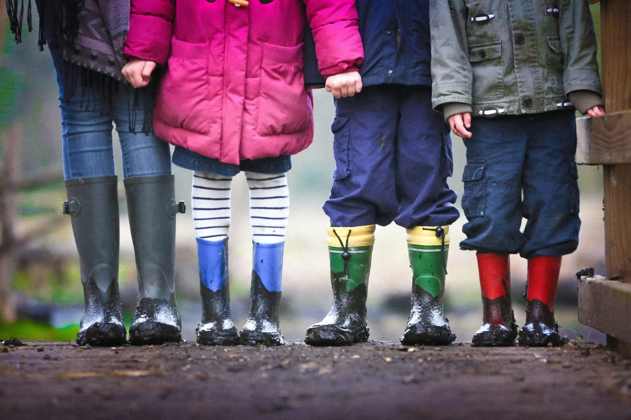 Children standing together wearing colorful rain boots